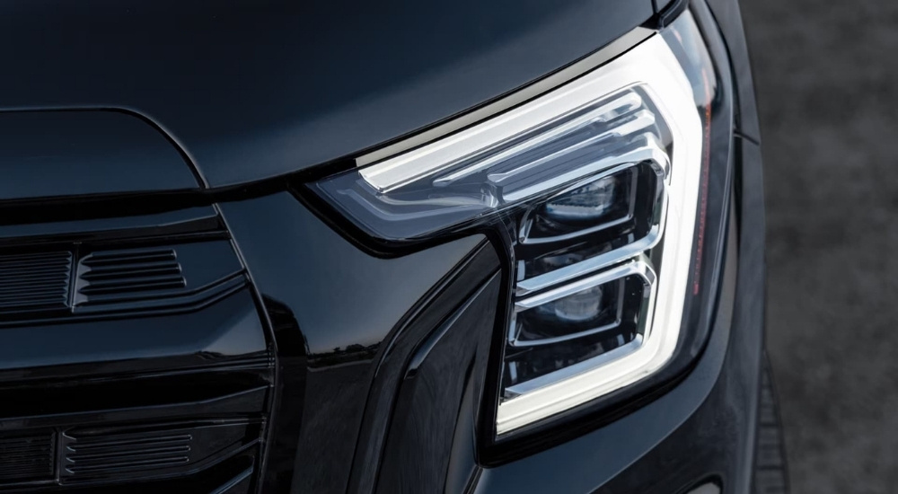 A close-up shows the driver side headlight on a black 2025 GMC Terrain for sale.