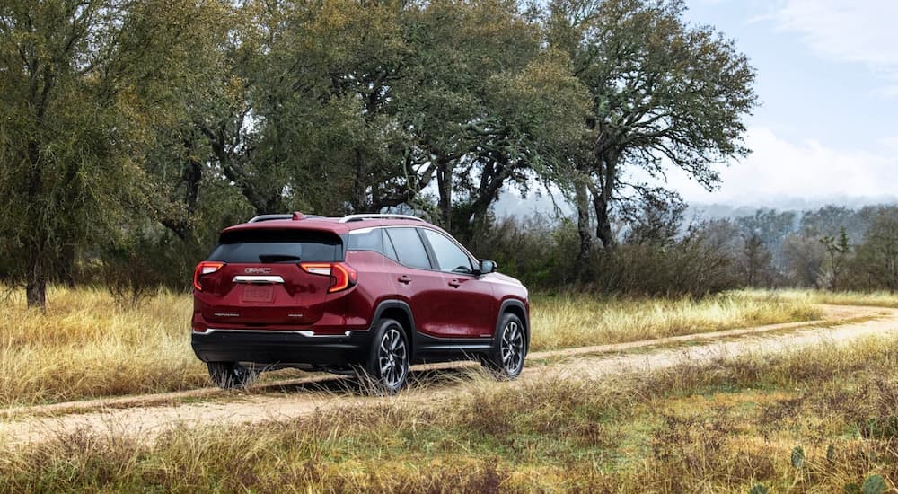 A red 2022 GMC Terrain driving to view a used GMC for sale.