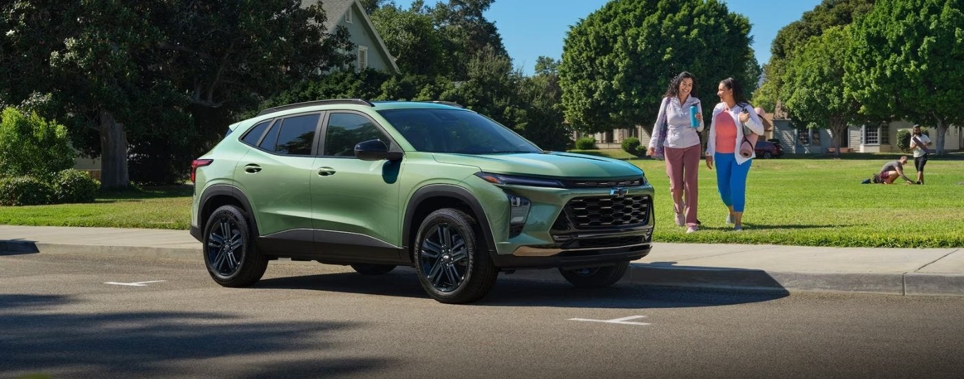 A green 2026 Chevy Trax ACTIV shown parked by a field and people.