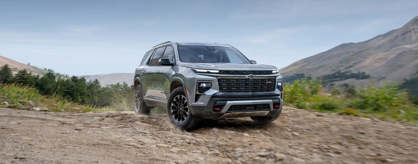 Silver 2025 Chevy Traverse driving off-road on a hill
