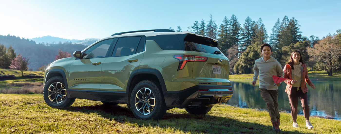 Green 2026 Chevy Equinox ACTIV parked on grass with kids running past