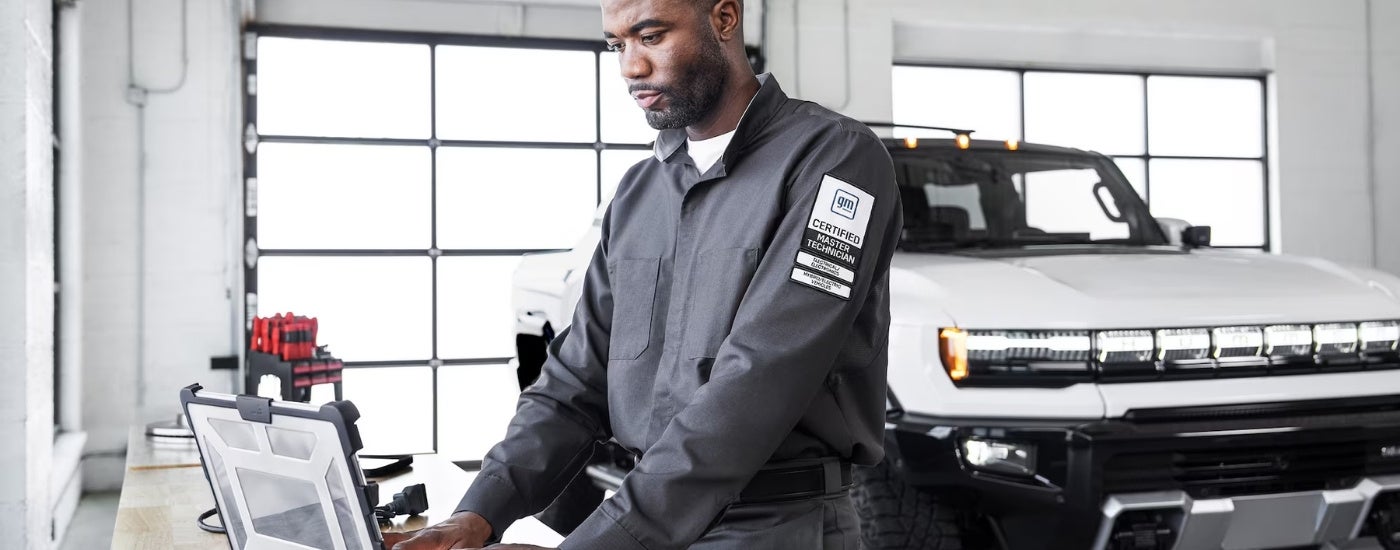 A tech is shown using a laptop near a white 2025 GMC Hummer EV.