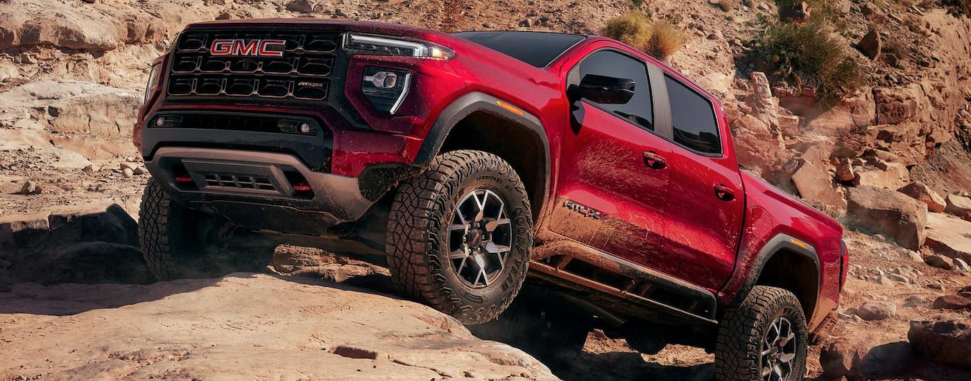Red 2025 GMC Canyon parked on a rocky cliff.