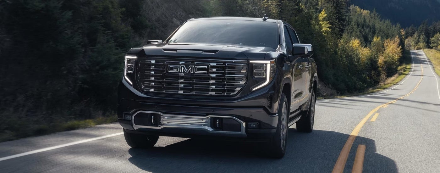 A black 2025 GMC Sierra 1500 Denali is driving on an open road.