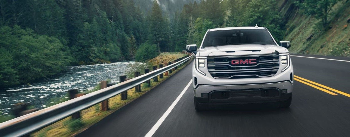 Front a white 2024 GMC Sierra 1500 SLE for sale near Paducah driving down an open road.