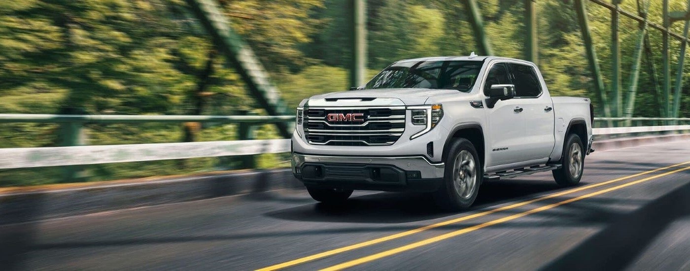White 2025 GMC Sierra 1500 driving across a bridge.